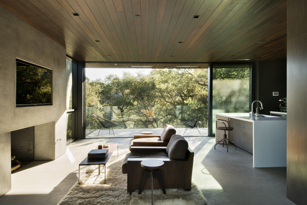 Источник вдохновения для домашнего уюта: открытая гостиная комната в современном стиле с бетонным полом, стандартным камином и телевизором на стене