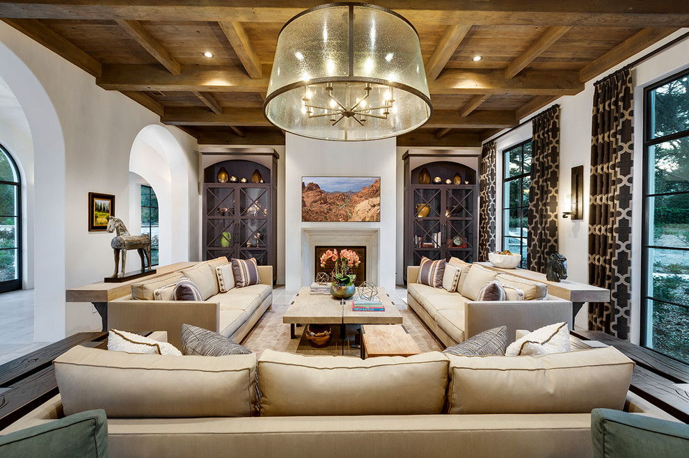 Идея дизайна: огромная открытая гостиная комната в средиземноморском стиле с белыми стенами, полом из известняка и телевизором на стене