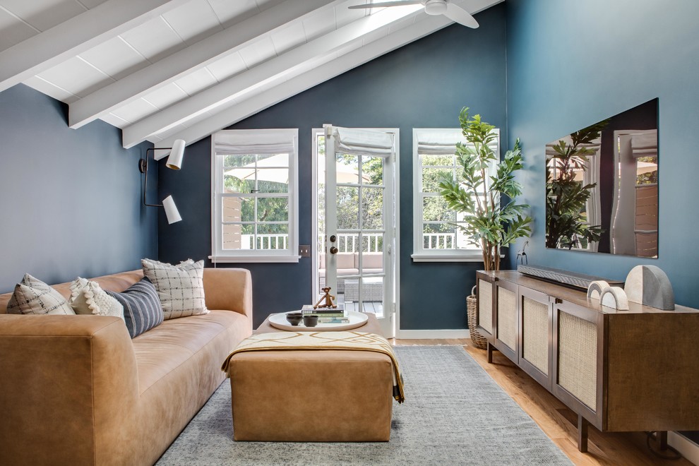 Abgetrenntes Skandinavisches Wohnzimmer mit blauer Wandfarbe, braunem Holzboden, TV-Wand und braunem Boden in Orange County