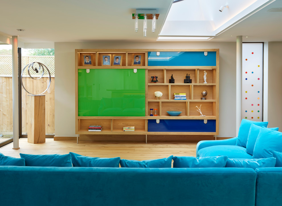 Modelo de salón para visitas cerrado contemporáneo de tamaño medio con suelo de madera clara y televisor retractable