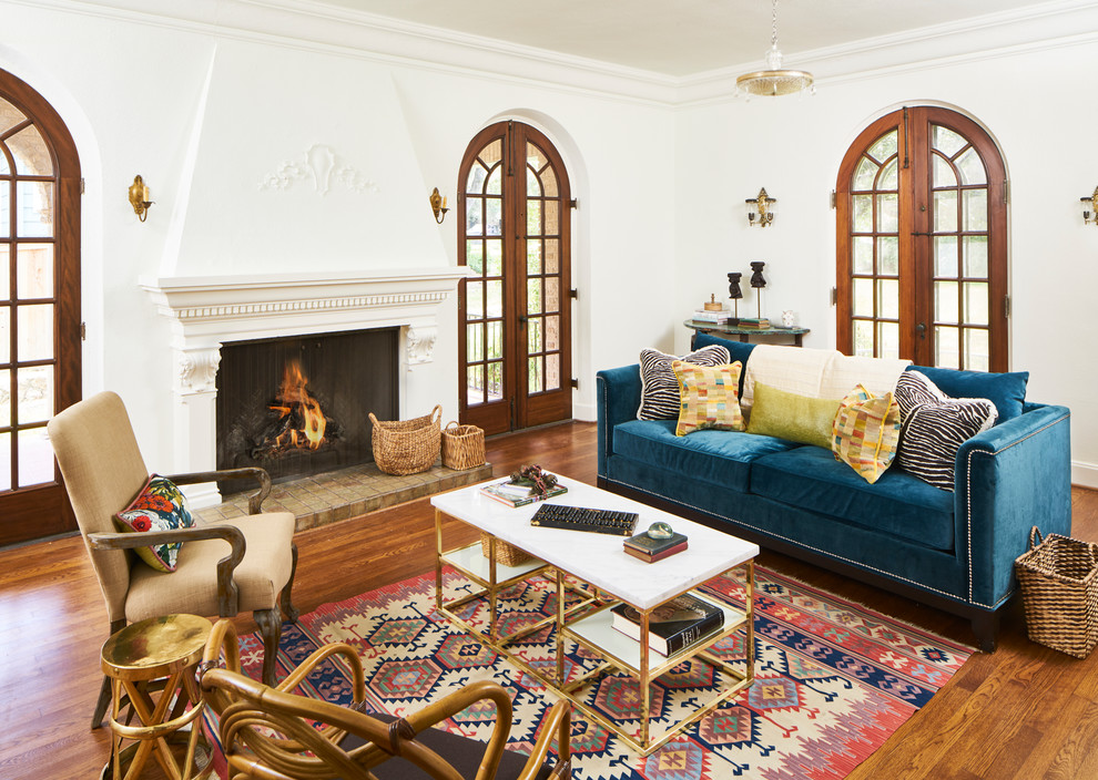 Abgetrenntes Mediterranes Wohnzimmer mit weißer Wandfarbe, braunem Holzboden, Kamin und braunem Boden in Austin