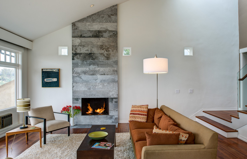 Пример оригинального дизайна: парадная гостиная комната в современном стиле с белыми стенами, паркетным полом среднего тона, фасадом камина из камня и ковром на полу