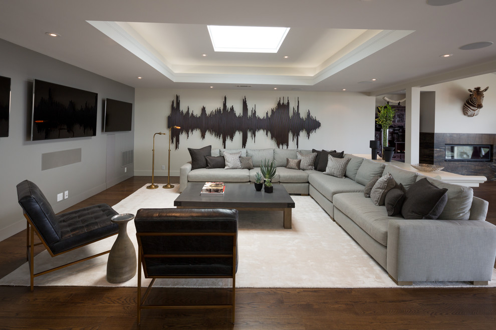 Стильный дизайн: открытая гостиная комната в современном стиле с серыми стенами, темным паркетным полом и телевизором на стене - последний тренд