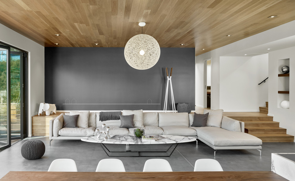 На фото: открытая гостиная комната среднего размера в стиле модернизм с серыми стенами и бетонным полом без камина, телевизора