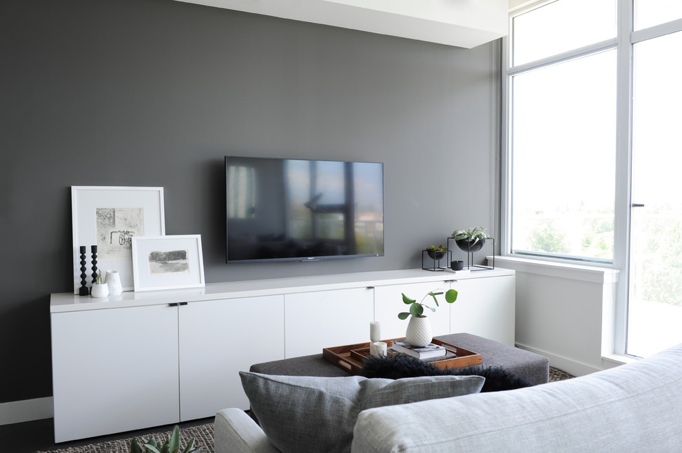 Aménagement d'un petit salon contemporain ouvert avec un mur gris, un sol en bois brun et un téléviseur fixé au mur.