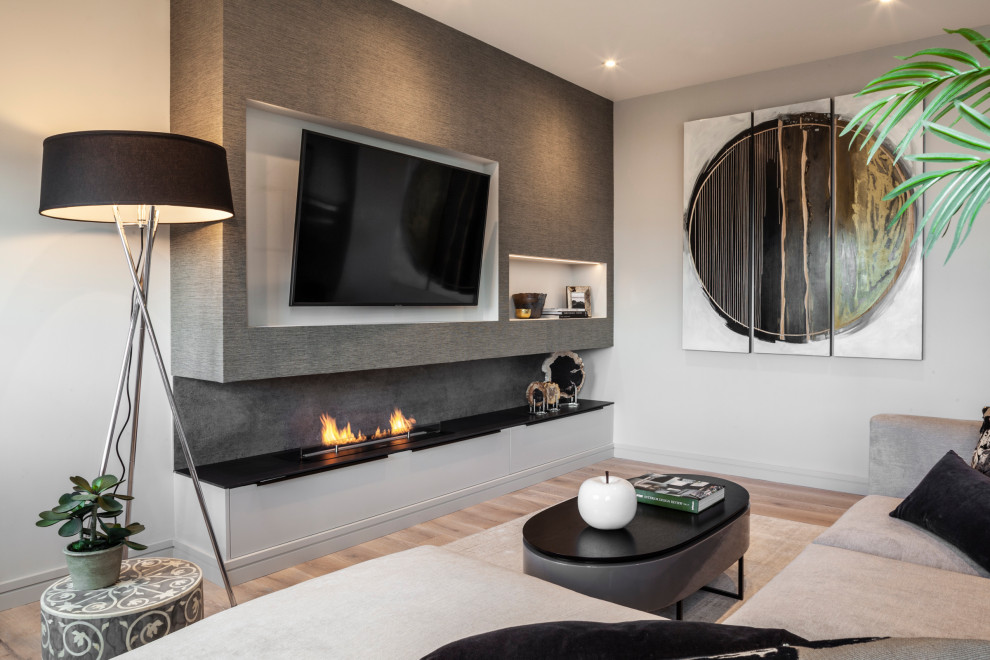 Imagen de salón abierto contemporáneo de tamaño medio con suelo de madera en tonos medios, chimenea de doble cara, marco de chimenea de hormigón, televisor colgado en la pared y suelo gris