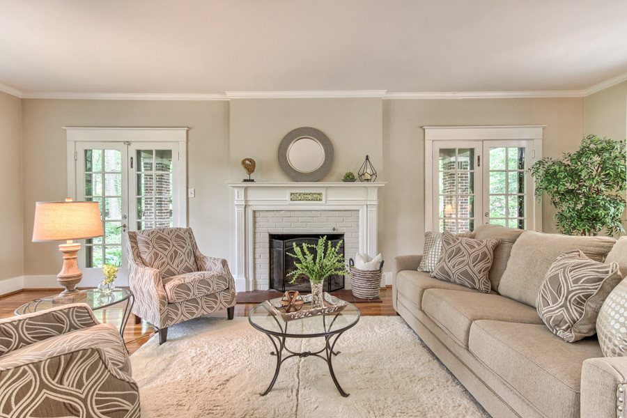 Foto di un soggiorno stile americano chiuso con sala formale, pareti beige, parquet chiaro, camino classico e cornice del camino in mattoni