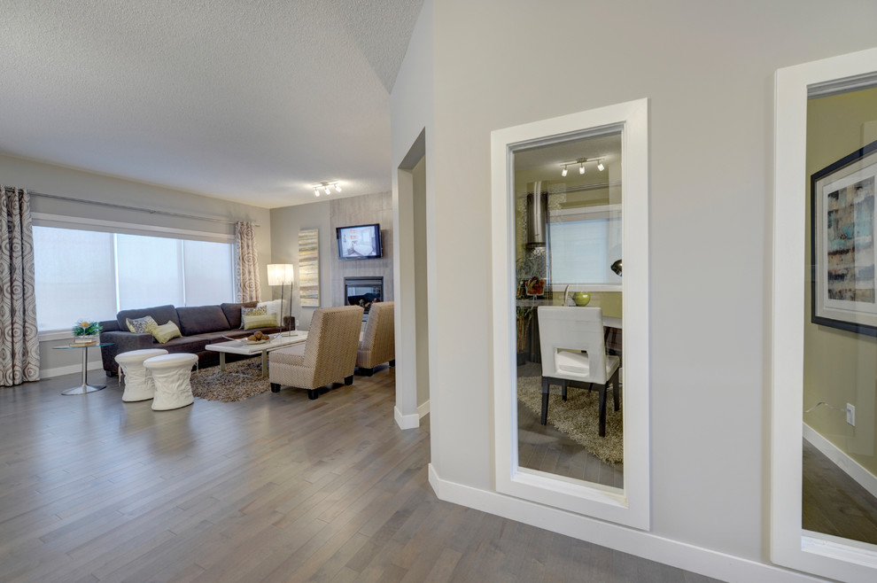 Example of a mid-sized transitional open concept light wood floor living room design in Edmonton with gray walls, a standard fireplace, a tile fireplace and a wall-mounted tv