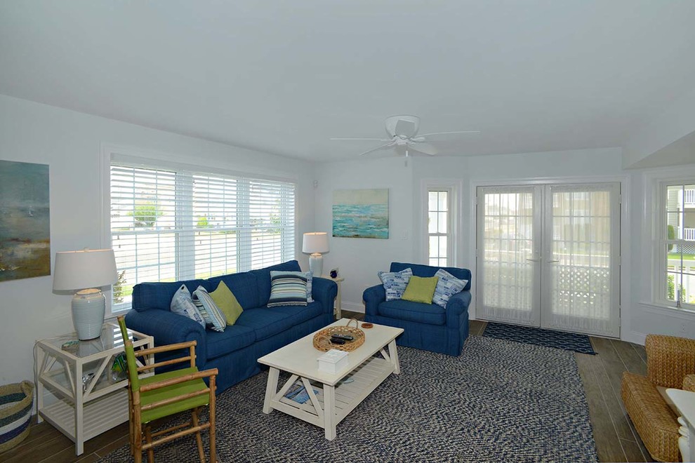 Cette image montre un salon marin de taille moyenne et ouvert avec une salle de réception, un mur bleu, parquet foncé, aucune cheminée, aucun téléviseur et un sol marron.