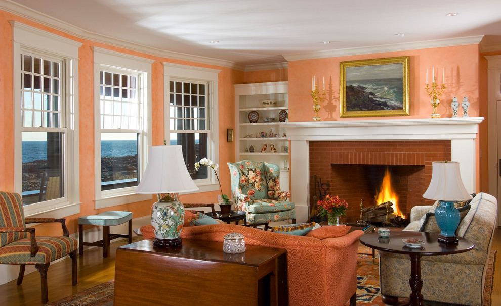 ポートランド(メイン)にある高級な中くらいなトラディショナルスタイルのおしゃれなリビング (オレンジの壁、無垢フローリング、標準型暖炉、レンガの暖炉まわり、テレビなし) の写真