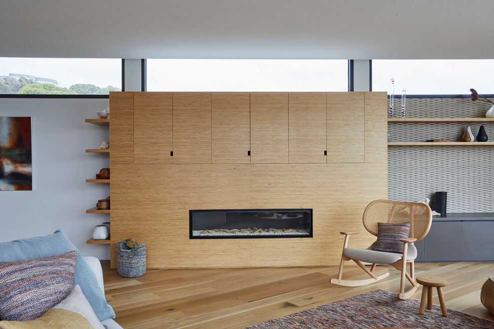 Cette image montre un très grand salon design avec un mur blanc, un sol en bois brun et une cheminée ribbon.