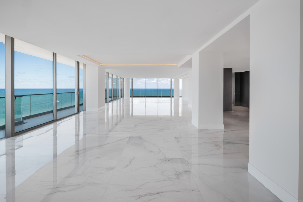 Réalisation d'un grand salon minimaliste ouvert avec un mur blanc, un sol en marbre et un sol blanc.