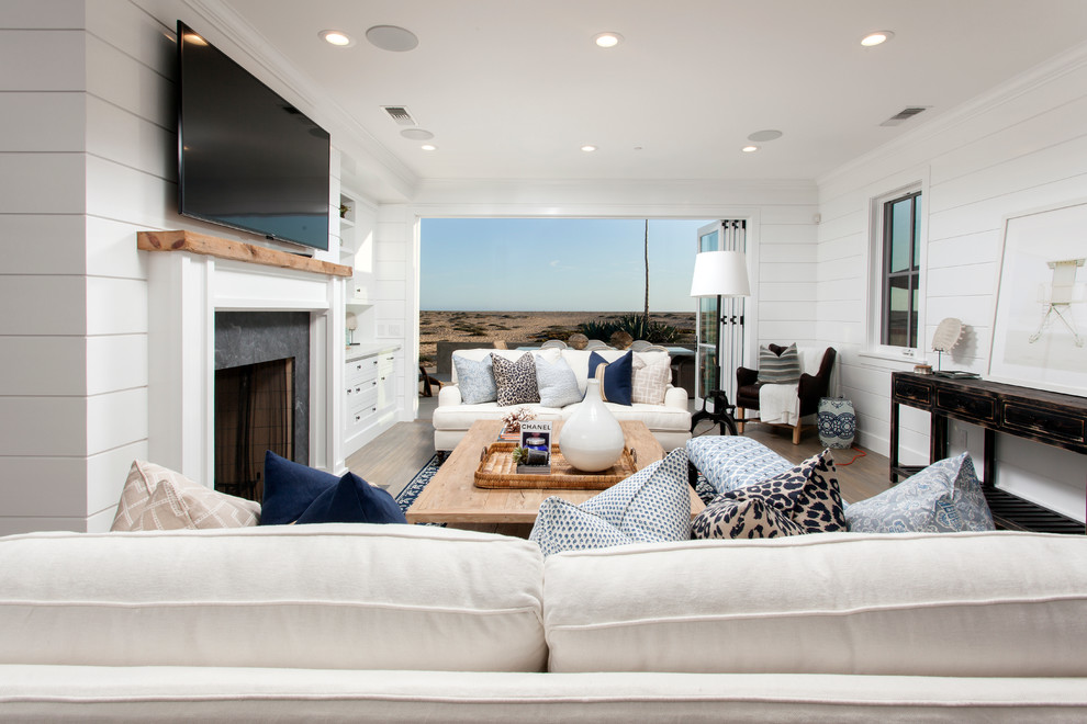 Inspiration for a large coastal open concept dark wood floor living room remodel in Orange County with white walls, a standard fireplace, a stone fireplace and a wall-mounted tv