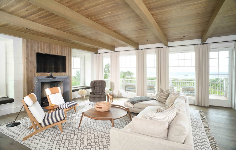 Beach style open plan living room in Charleston with white walls, dark hardwood flooring, a standard fireplace, a wall mounted tv and brown floors.