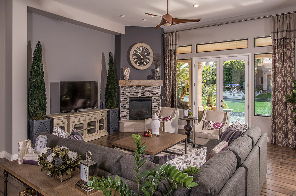 Cette image montre un salon traditionnel de taille moyenne et ouvert avec un mur violet, un sol en bois brun, une cheminée d'angle, un manteau de cheminée en carrelage et un téléviseur indépendant.