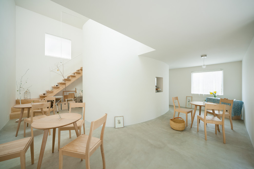 Ejemplo de salón abierto de tamaño medio sin televisor con paredes blancas, suelo de cemento y suelo gris