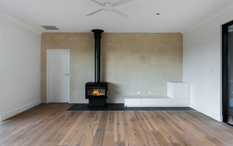 Réalisation d'un salon minimaliste de taille moyenne et ouvert avec un mur blanc, un sol en bois brun, une cheminée standard, un manteau de cheminée en carrelage, aucun téléviseur et un sol marron.