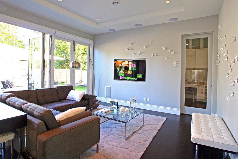 Bild på ett funkis vardagsrum, med grå väggar och en väggmonterad TV