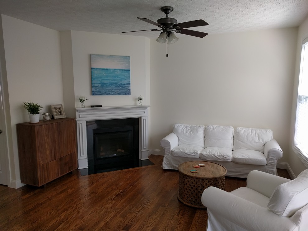シンシナティにあるお手頃価格の小さなビーチスタイルのおしゃれなLDK (白い壁、無垢フローリング、コーナー設置型暖炉、石材の暖炉まわり、内蔵型テレビ) の写真