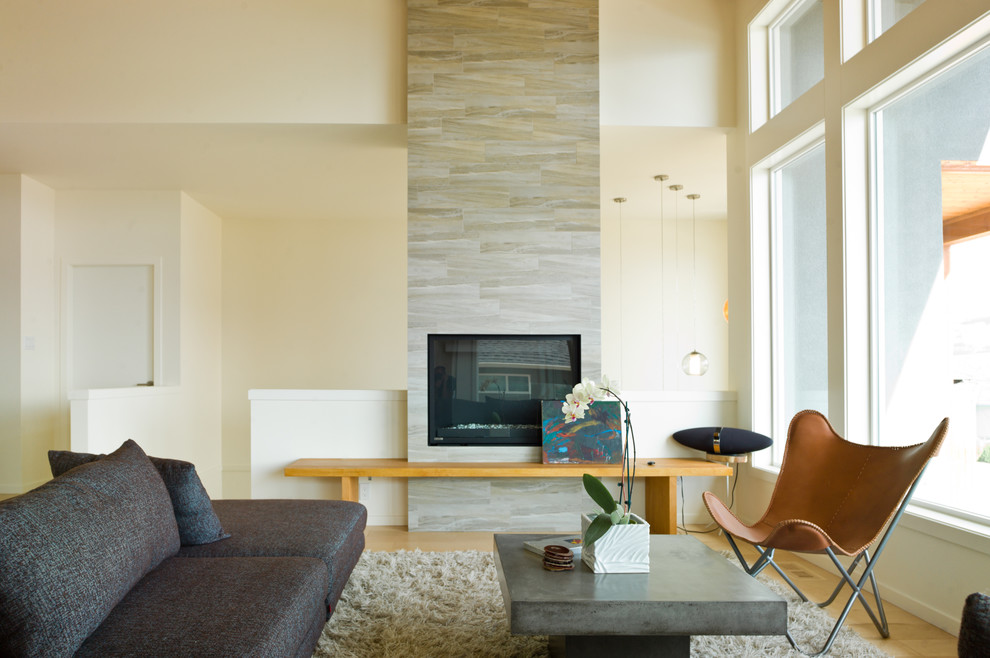 This is an example of a medium sized modern formal enclosed living room in Vancouver with a tiled fireplace surround, white walls, light hardwood flooring, a standard fireplace, no tv and beige floors.