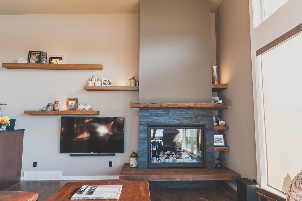 Стильный дизайн: парадная, открытая гостиная комната среднего размера в стиле рустика с коричневыми стенами, темным паркетным полом, стандартным камином, фасадом камина из камня и телевизором на стене - последний тренд