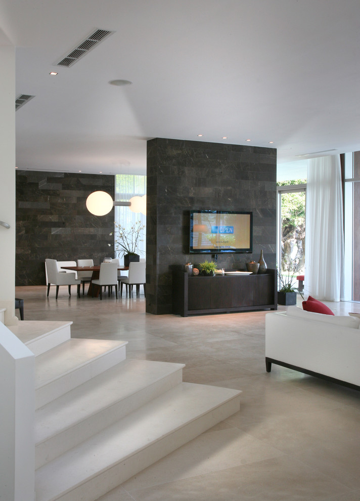 Aménagement d'un grand salon moderne ouvert avec un mur blanc, un sol en calcaire et un téléviseur fixé au mur.