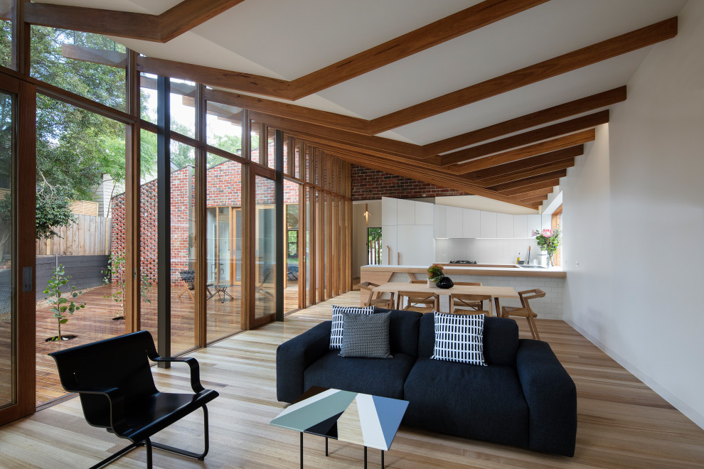 Kleines, Offenes Modernes Wohnzimmer mit weißer Wandfarbe, braunem Holzboden und braunem Boden in Melbourne