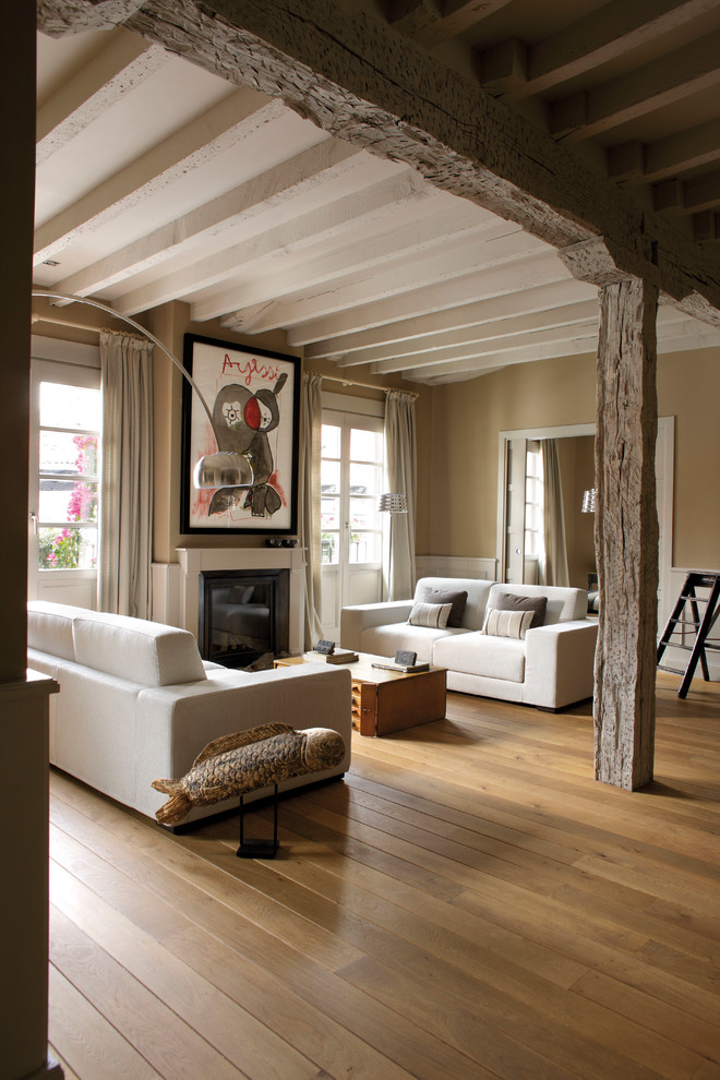 Exemple d'un grand salon nature ouvert avec un mur beige, un sol en bois brun, une cheminée standard, une salle de réception et aucun téléviseur.