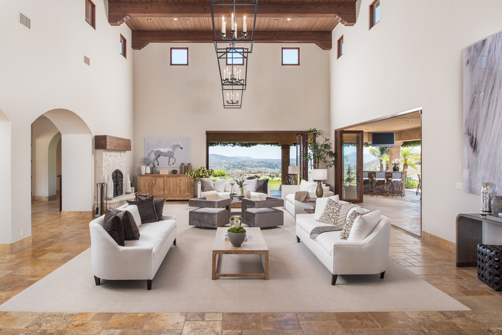 Идея дизайна: гостиная комната в средиземноморском стиле с белыми стенами, стандартным камином, фасадом камина из камня и коричневым полом