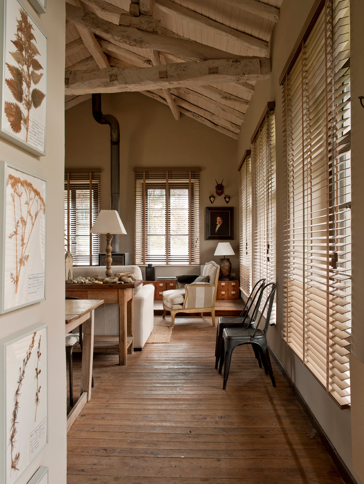 Modelo de salón abierto campestre grande con suelo de madera en tonos medios y estufa de leña