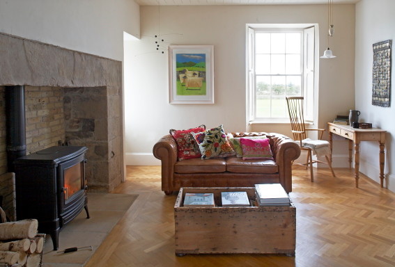 Example of a mid-sized classic enclosed light wood floor living room design in Other with white walls, a wood stove, a stone fireplace and no tv