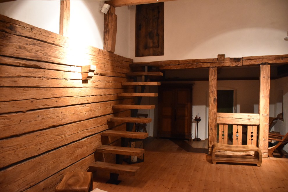 Immagine di un soggiorno stile rurale con pareti bianche, pavimento in legno massello medio, stufa a legna, cornice del camino in metallo e travi a vista