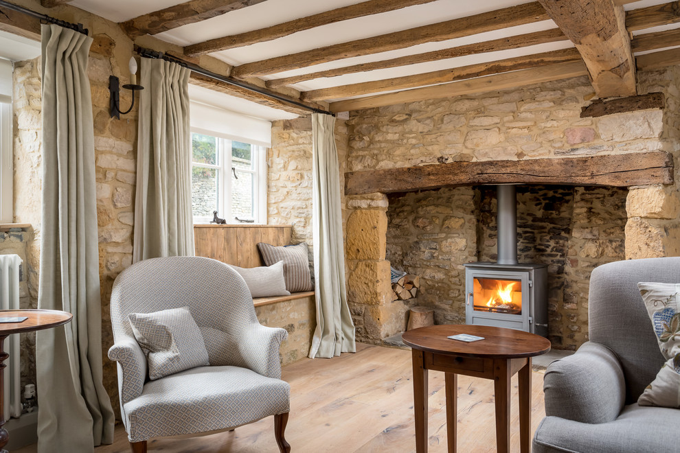 Example of a small light wood floor living room design in Gloucestershire with a wood stove and a stone fireplace
