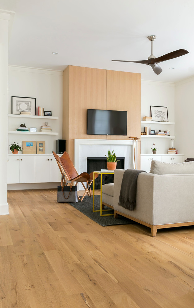 Cette image montre un salon minimaliste de taille moyenne et ouvert avec un mur blanc, parquet clair, une cheminée standard, un manteau de cheminée en pierre, un téléviseur fixé au mur et un sol marron.