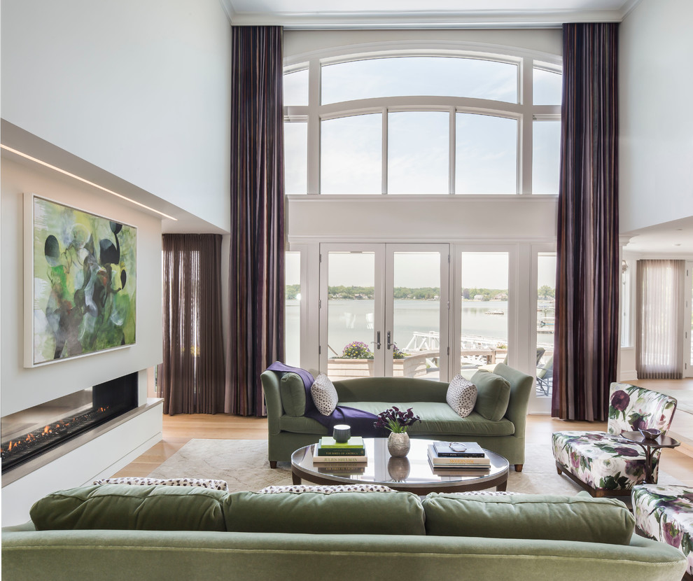 Imagen de salón para visitas abierto actual grande sin televisor con paredes blancas, suelo de madera clara, chimenea de doble cara y cortinas