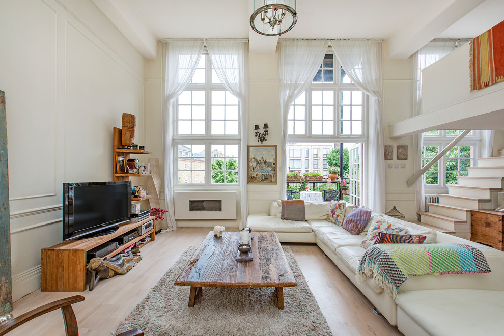 Klassisches Wohnzimmer ohne Kamin mit beiger Wandfarbe, hellem Holzboden und freistehendem TV in London