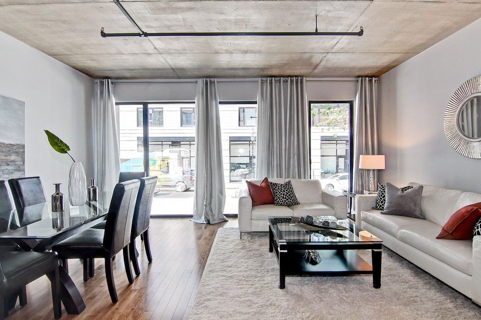 Diseño de salón abierto urbano de tamaño medio con paredes grises y suelo de madera en tonos medios