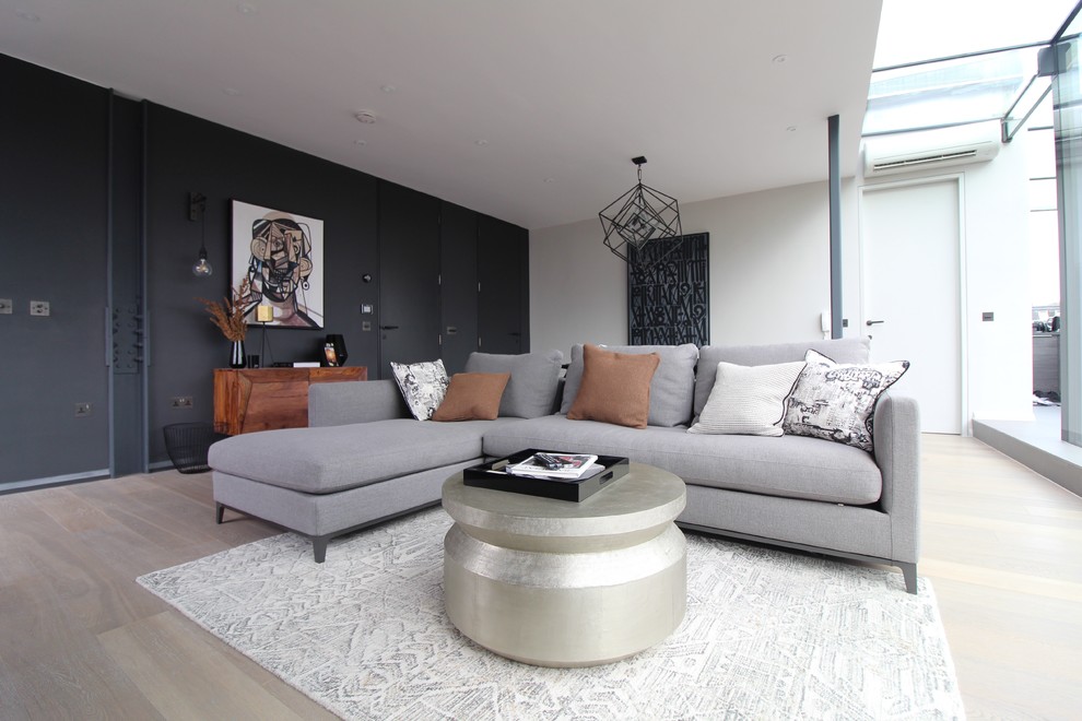 This is an example of a medium sized modern enclosed living room in London with white walls and light hardwood flooring.