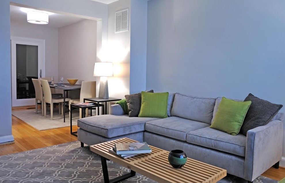 Esempio di un grande soggiorno design aperto con pareti blu, pavimento in legno massello medio e TV a parete