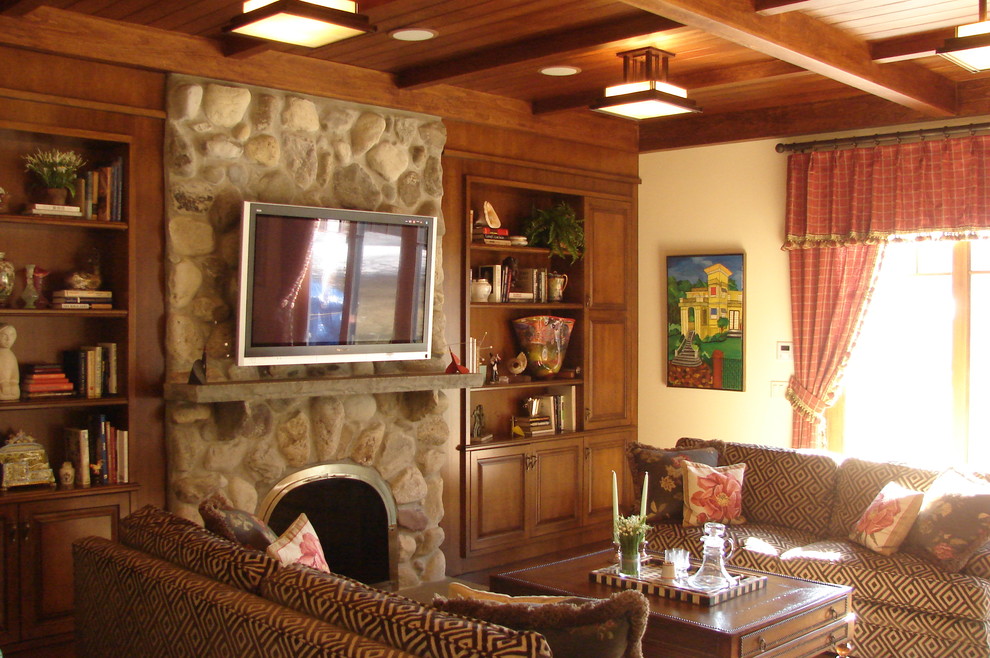 На фото: гостиная комната в стиле рустика с фасадом камина из камня и красивыми шторами