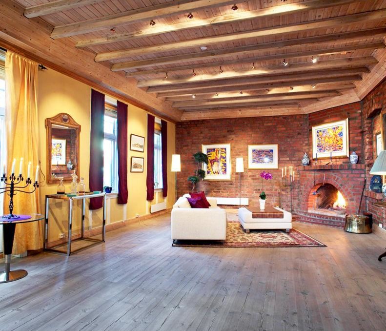 Modelo de salón para visitas urbano grande con paredes amarillas, suelo de madera clara, chimenea de esquina y marco de chimenea de ladrillo