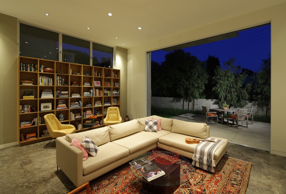 Foto på ett funkis vardagsrum, med ett bibliotek, beige väggar och betonggolv