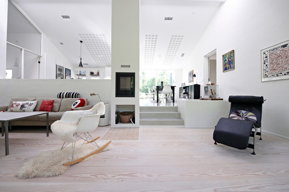 Immagine di un ampio soggiorno contemporaneo aperto con sala formale, pareti bianche, pavimento in legno verniciato, stufa a legna e cornice del camino in mattoni