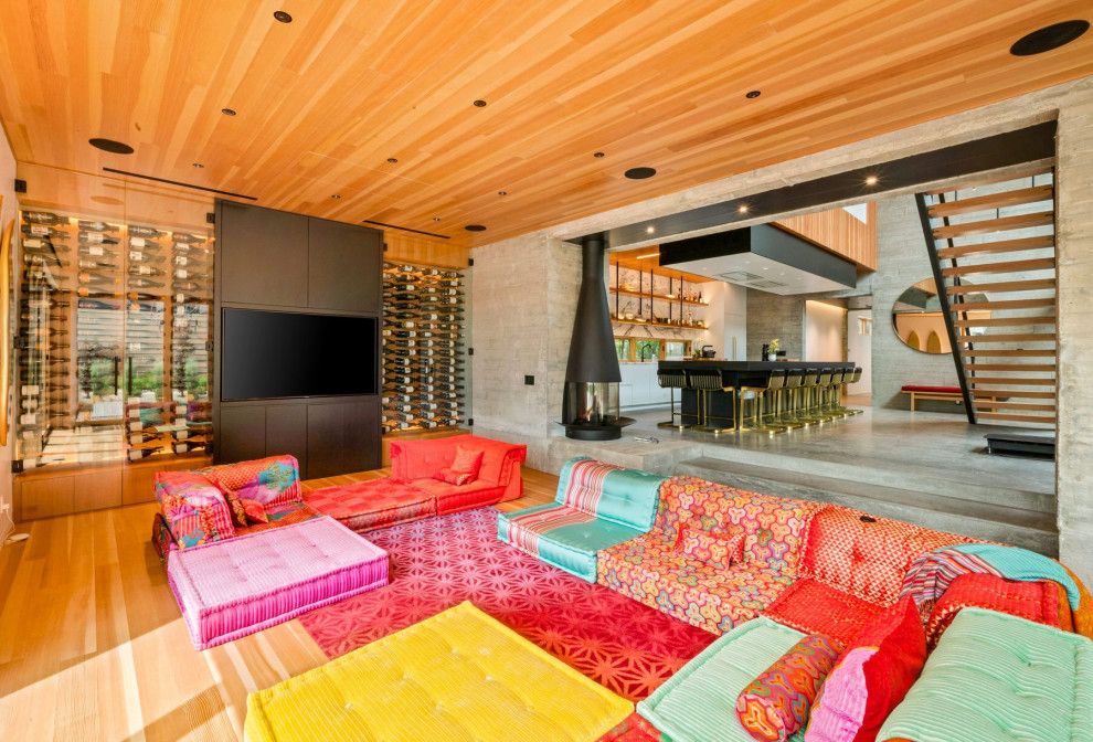 Offenes Modernes Wohnzimmer mit hellem Holzboden, Eckkamin, Kaminumrandung aus Beton, Multimediawand, Holzdecke und beigem Boden in Sonstige