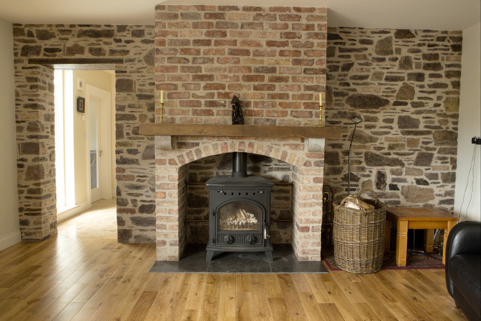 Imagen de salón abierto rural de tamaño medio con suelo de madera en tonos medios, estufa de leña y marco de chimenea de ladrillo