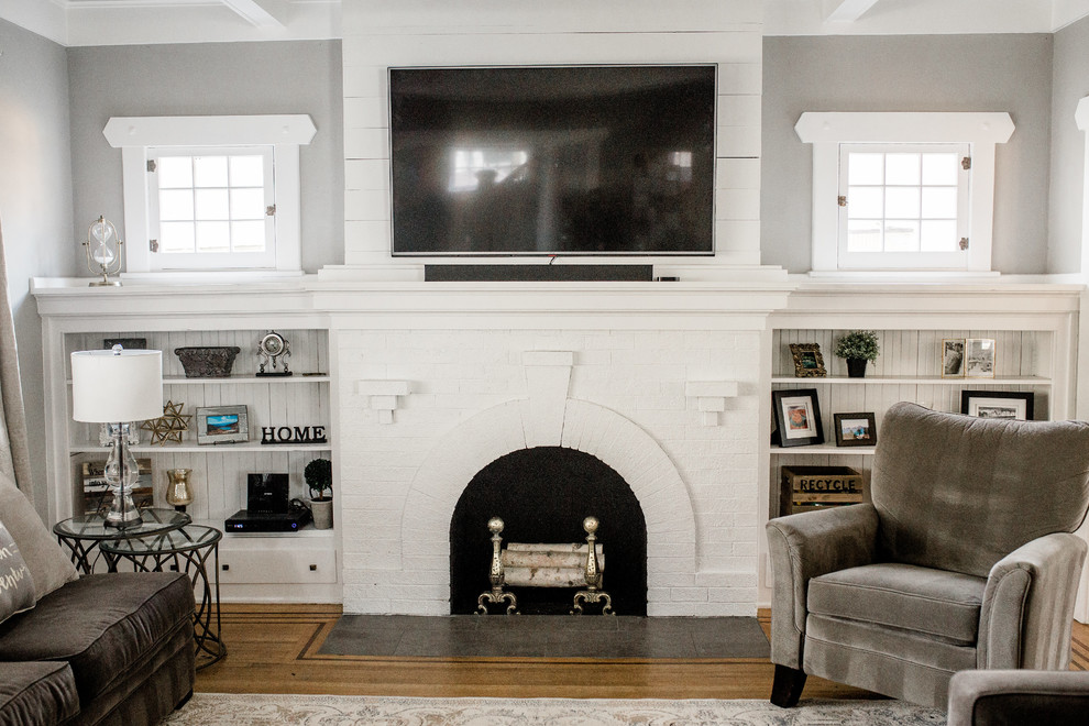 Inspiration for a medium sized traditional enclosed living room in Seattle with grey walls, dark hardwood flooring, a standard fireplace, a brick fireplace surround, a wall mounted tv and brown floors.