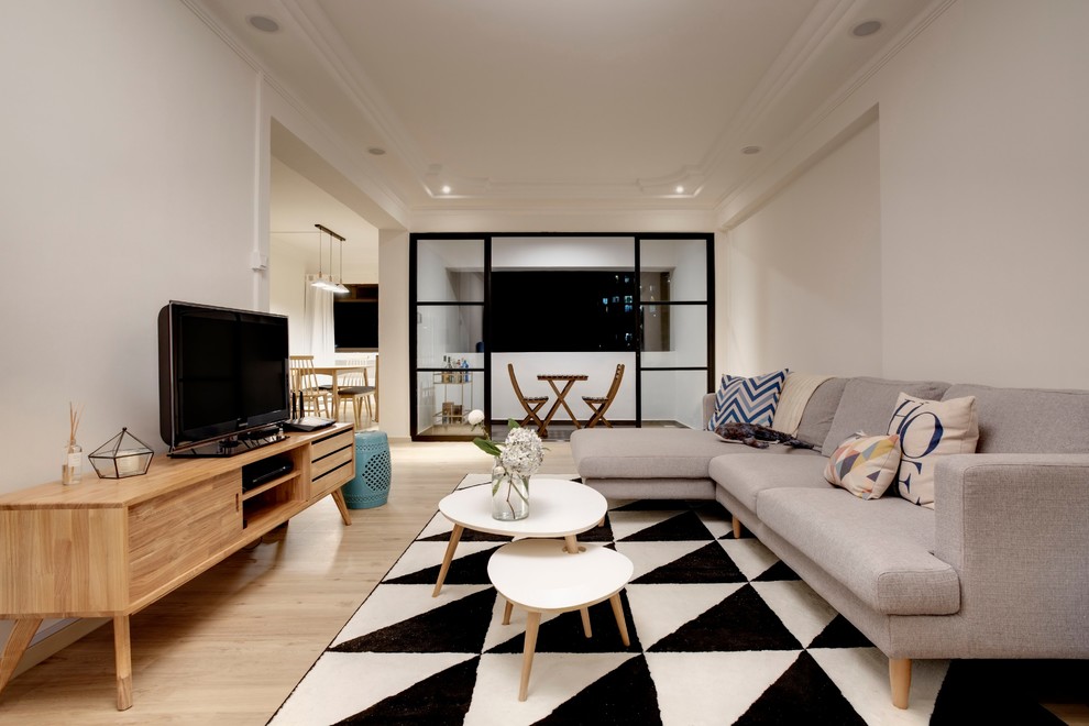 This is an example of a modern open plan living room in Singapore with white walls, light hardwood flooring, a freestanding tv and beige floors.