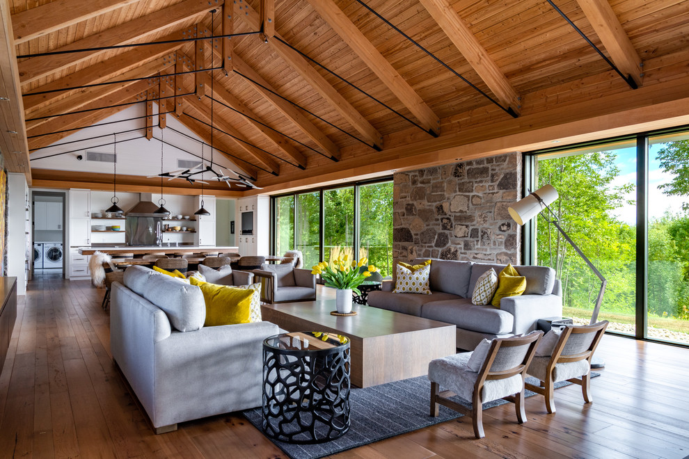Ejemplo de salón para visitas abierto de estilo de casa de campo sin chimenea con suelo de madera en tonos medios y piedra