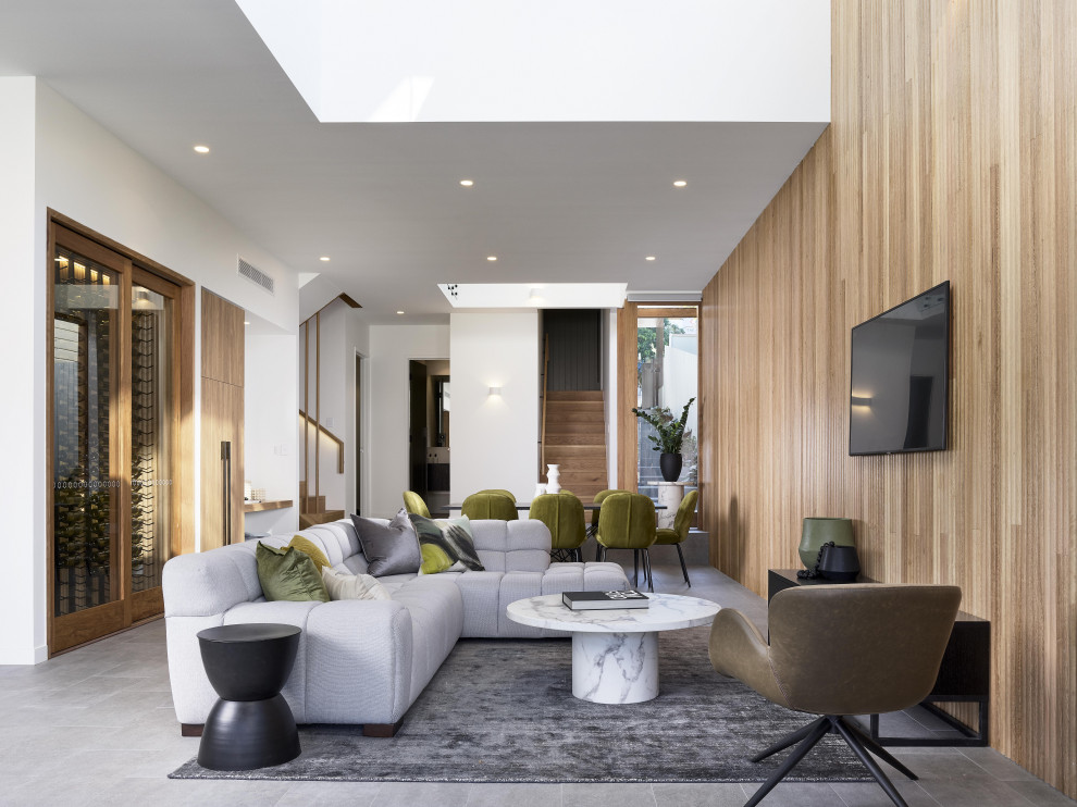 Modelo de salón abierto minimalista con paredes blancas, televisor colgado en la pared y suelo gris