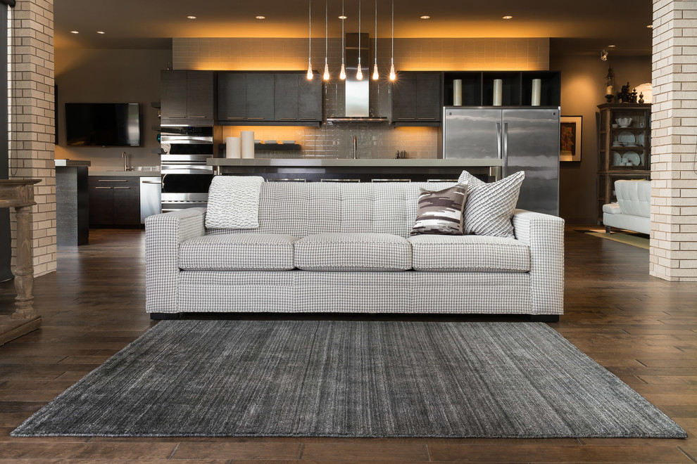 This is an example of a large industrial open plan living room in Boston with beige walls and dark hardwood flooring.